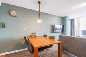 comedor con mesa y reloj en la pared en Appartementencomplex Juliana 124, en De Koog