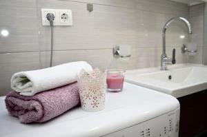 a bathroom with towels and a glass of pink liquid at Apartments Karla in Stanići