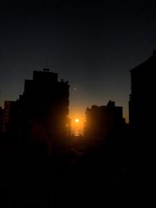 a city skyline with the sun setting in the distance at Espaçoso e a 450m da praia Itapema in Itapema