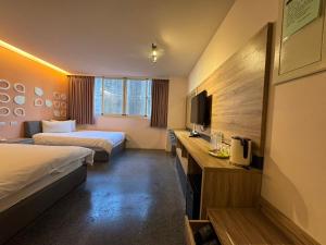 a hotel room with two beds and a television at Travel Light Hotel in Puli