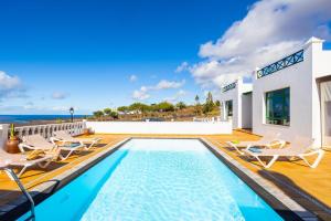 basen z krzesłami i oceanem w tle w obiekcie Villa Sol Y Mar w mieście Yaiza