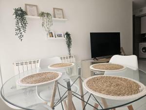 a glass table with four chairs and a television at La Tallada in Caspe