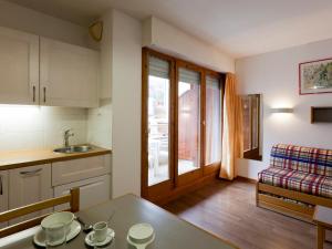 eine Küche und ein Wohnzimmer mit einem Tisch und einer Couch in der Unterkunft Studio Confortable pour 2 Personnes avec Balcon, Proche Télécabine et Spa à Brides-les-Bains - FR-1-512-114 in Brides-les-Bains