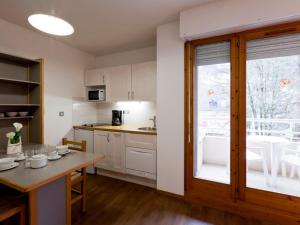 eine Küche mit weißen Schränken und einem Tisch und einem Fenster in der Unterkunft Studio Confortable pour 2 Personnes avec Balcon, Proche Télécabine et Spa à Brides-les-Bains - FR-1-512-114 in Brides-les-Bains + 15 Fotos