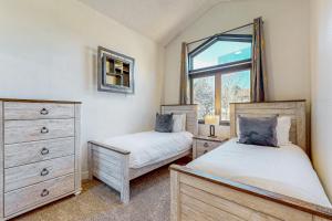 two beds in a bedroom with a window and a dresser at Cozy Mountain Retreat in Flagstaff