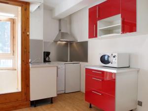 a kitchen with red and white cabinets and a microwave at Studio 4 pers centre-ville avec WiFi, parking et animaux acceptés - FR-1-512-234 in Brides-les-Bains
