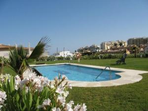 a swimming pool in the middle of a lawn with flowers at La Cala de Mijas, groundfloor 2 bed apartment steps away from the beach in Mijas Costa