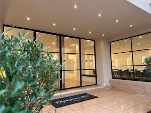 eine Lobby mit Glasfenstern und einer Pflanze in der Unterkunft Olympian Altis Hotel in Olympia