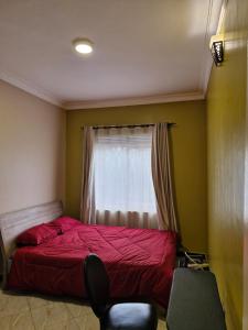 ein Schlafzimmer mit einem roten Bett und einem Fenster in der Unterkunft Kyanja Luxury Suites in Kampala