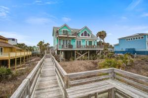 a house on the beach with a wooden boardwalk at The Lighthouse Keeper in Folly Beach