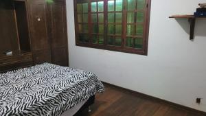 a room with a bed with a black and white blanket at Pousada Serrana in Coimbra