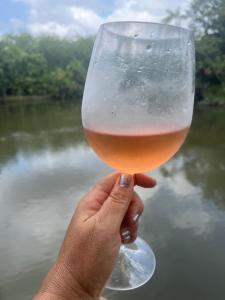 a person holding a glass of beer in front of a river at Chalé Encantos do Una in Morros