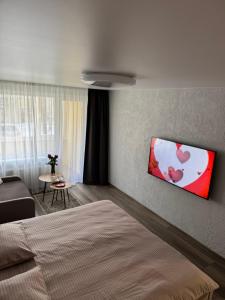 a bedroom with a bed with a painting of hearts on the wall at Taikos apartamentas in Mažeikiai