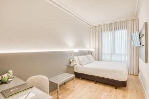 a bedroom with a bed and a desk and a table at Sercotel Arenal Bilbao in Bilbao