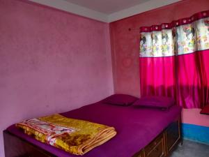 sypialnia z fioletowym łóżkiem i różowymi zasłonami w obiekcie Hotel svr w mieście Padmalābhpur