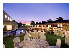 un salón de banquetes con mesas y sillas blancas y una piscina en Hotel Cezaria, en Ioannina
