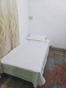 a white bed sitting in a corner of a room at Shree Dhaam Homestay in Faizābād +1 photo