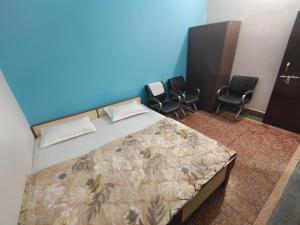 a bedroom with a bed with chairs and a blue wall at Shree Dhaam Homestay in Faizābād
