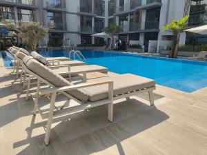 a group of lounge chairs sitting next to a swimming pool at Boutique Loft, Stylish, Cozy and Luxurious style apartment in wonderful building with 2 Pools & Gym in Dubai