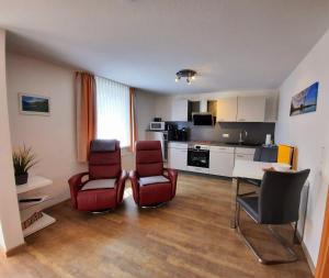 a living room with two chairs and a table and a kitchen at Ferienwohnungen Schäferhaus, incl MeineCardPlus in Willingen