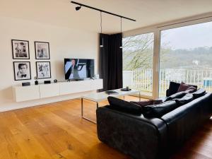 un salon avec un canapé noir et une télévision dans l'établissement Stilvolles 007 Penthouse nähe Düsseldorf Köln, à Wuppertal