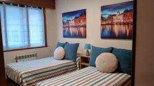 two beds in a room with paintings on the wall at Apartamento in Ferrol