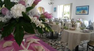una sala da pranzo con tavoli con fiori bianchi e rosa di Hotel Camelia a Rimini