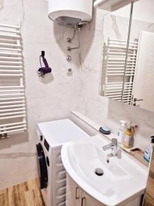 a white bathroom with a sink and a mirror at Apartment Modern Nest in Zenica