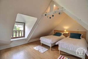 two beds in a attic bedroom with a window at Domaine de la motte in Plourhan
