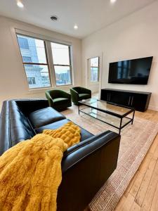 a living room with a black leather couch and a tv at Condo C - Gallery Suites Downtown Marion in Warren