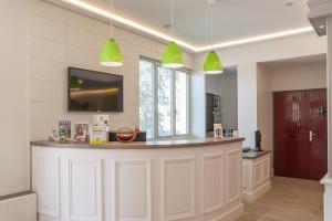 a kitchen with a bar with green pendant lights at LOGIS Hotel l'Escargotière Dijon Sud - Chenove in Chenôve