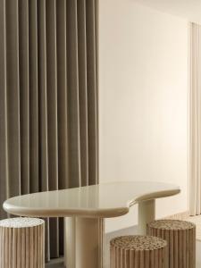 a white table and stools in a room with curtains at Rose Hôtel Invisible in Quebec City