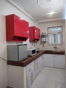 a kitchen with red cabinets and a microwave at Cozy stay- A Home Away From Home in Gurgaon