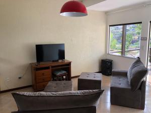 a living room with a couch and a flat screen tv at Casa 6 Mares de Búzios - 5 minutos a pé da Rua das Pedras in Búzios