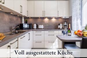 a kitchen with white cabinets and a table with a bowl of fruit at Ferienwohnung EDEN Apartment´s Vinum in Friedrichshafen