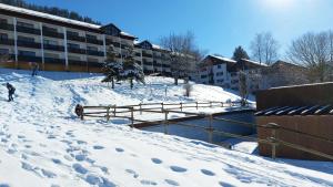 une personne marchant sur une piste enneigée à côté d'un bâtiment dans l'établissement Alp-Juwel - mit Hallenbad und Sauna - direkt an der Skipiste, à Missen-Wilhams