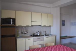 una cucina con mobili bianchi, un tavolo e un microonde di Corallo Aparment a Cala Gonone Altre 65 foto