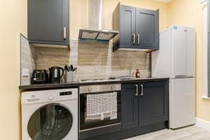 a kitchen with a washing machine and a refrigerator at Cozy Modern 1 Bed Flat Walsall Town Centre in Walsall