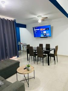 a living room with a table and chairs and a tv at Depa en Cancun con alberca in Cancún +15 photos
