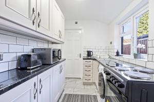 a kitchen with white cabinets and a stove top oven at Wolverhampton Townhouse - 3BR - Business & Leisure guests in Wolverhampton
