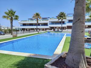 een zwembad met een palmboom voor een gebouw bij Salinas Luxury DaNuria in Torrevieja