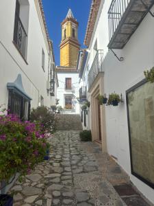 a cobblestone alley with a clock tower in the background at Casa de la Paz in Estepona