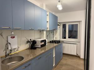 a kitchen with blue cabinets and a sink and a microwave at Michael2 in Galaţi