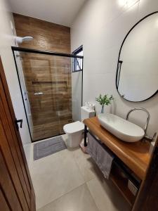 Un baño con lavabo, inodoro y espejo. en Casa de praia Brisa das Amendoeiras, en Palhoça