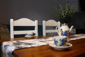 a table with two chairs and two cups and a vase at Apartamenty Baj na Polnej -Górski Azyl in PyzÃ³wka