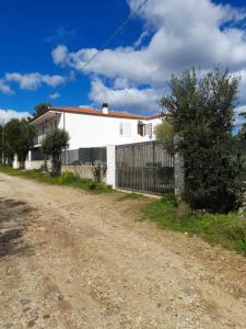 a white house with a fence on a dirt road at Casa relax Berchida in Capo Comino