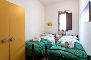 two beds in a room with green sheets and towels at Essenza di Zagara, 5min dalle spiagge e porto in Trapani +17 photos