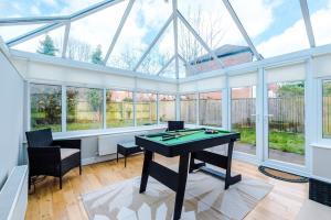 a conservatory with a pool table in a room with windows at Charming Townhome Retreat, close to Manchester in Manchester