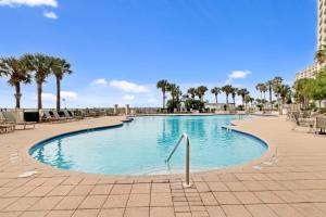 ein großer Swimmingpool mit Stühlen und Palmen in der Unterkunft 3BR 4BA Ground Floor Gulf Getaway in Gulf Shores