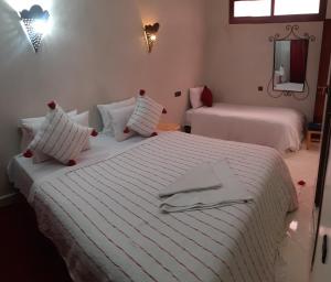a bedroom with two beds with white sheets and a mirror at Hôtel Restaurant Dar Al Madina in Tinerhir
